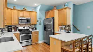 A kitchen with wooden cabinets, stainless steel appliances, and a white countertop.