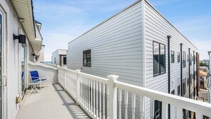 A balcony with a white railing, a blue chair, and a building with white siding.
