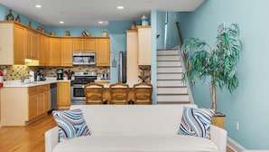 A spacious living area with a sofa, coffee table, and a staircase leading to an upper level.