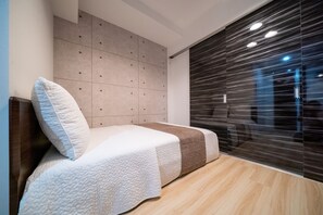 Ein modernes Schlafzimmer mit Bett, gepolstertem Kopfteil und einer Schiebetür aus Glas.