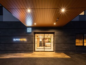 The exterior of a hotel with a modern design, featuring a wooden ceiling and a sign that reads "SUPERHOTEL". - Super Hotel Sendai Airport Inter (Natori)