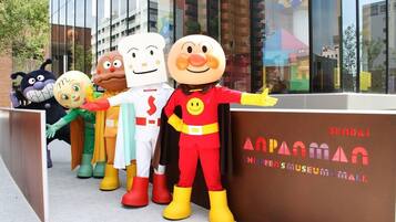 A group of cartoon character mascots standing in front of a building with a sign that reads "SEIBAL".