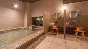 Ein Wellnessbereich mit Whirlpool, Holzschemeln, einem Spiegel und einem Waschbecken.