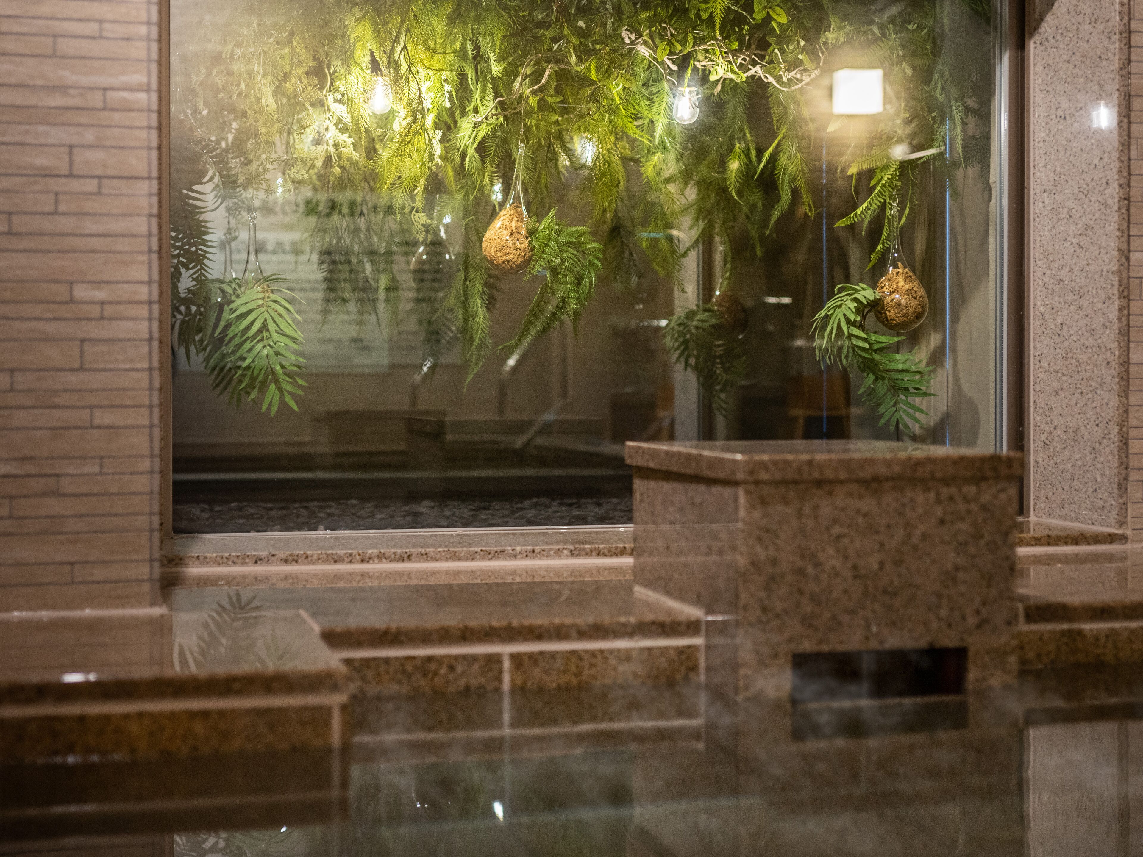 A lobby with a glass wall, a granite reception desk, and a staircase leading to an upper level.