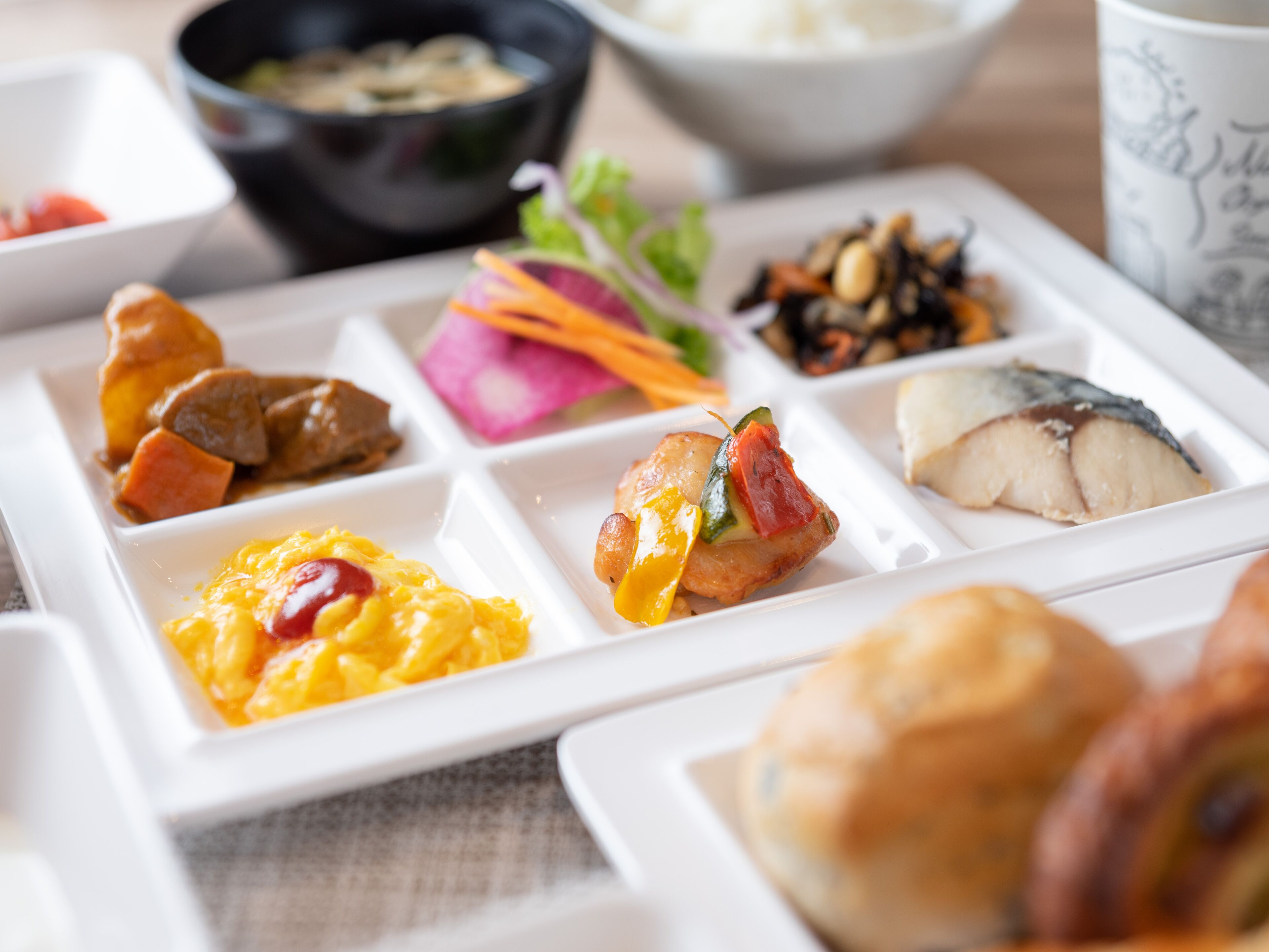A meal with various dishes including scrambled eggs, a fish fillet, and a side of vegetables.