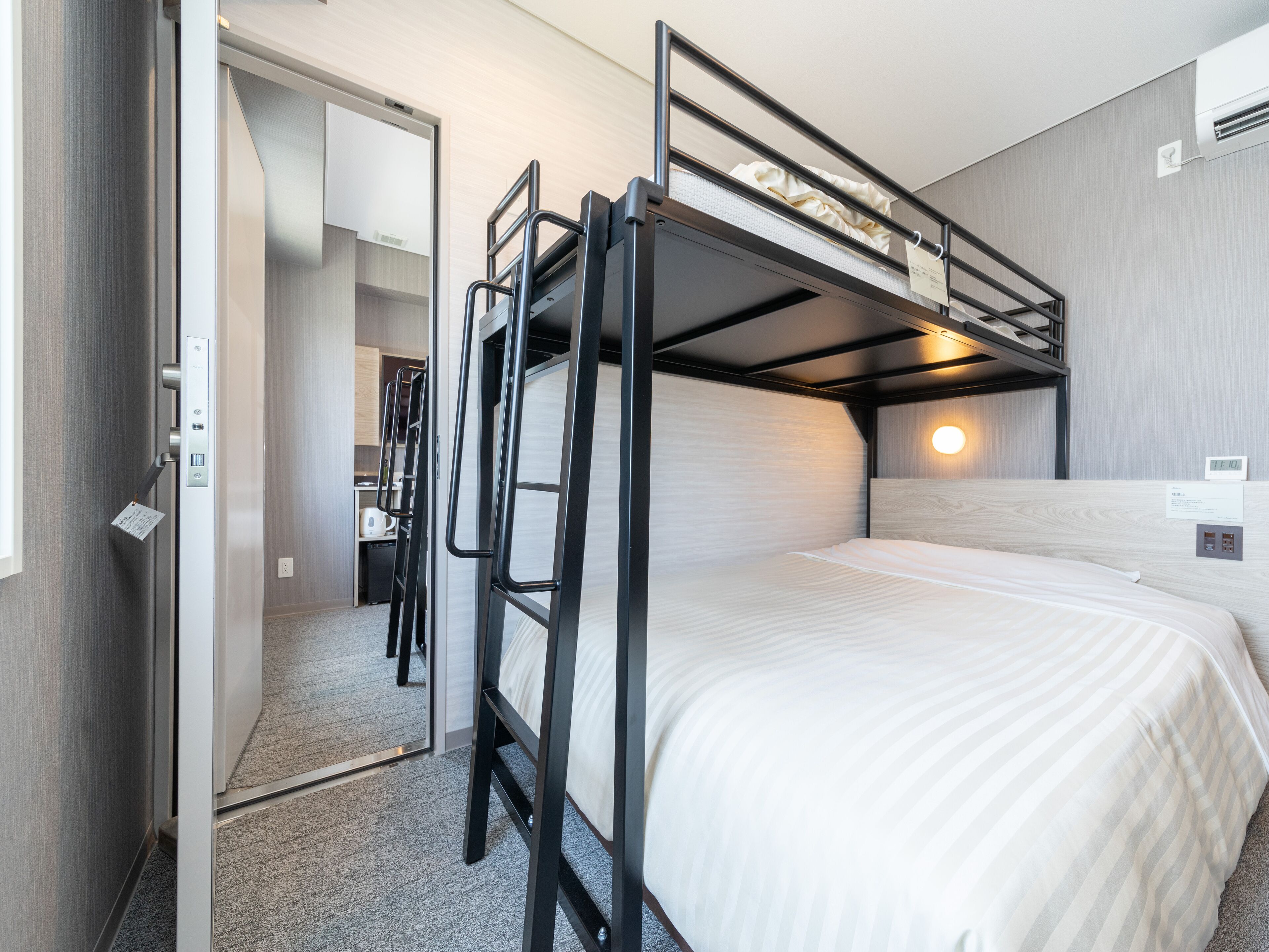 A bunk bed with a desk and chair, a small kitchenette, and a mirror.