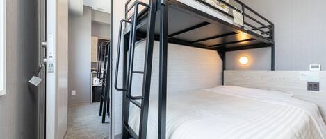 A bunk bed with a desk and chair, a small kitchenette, and a mirror.