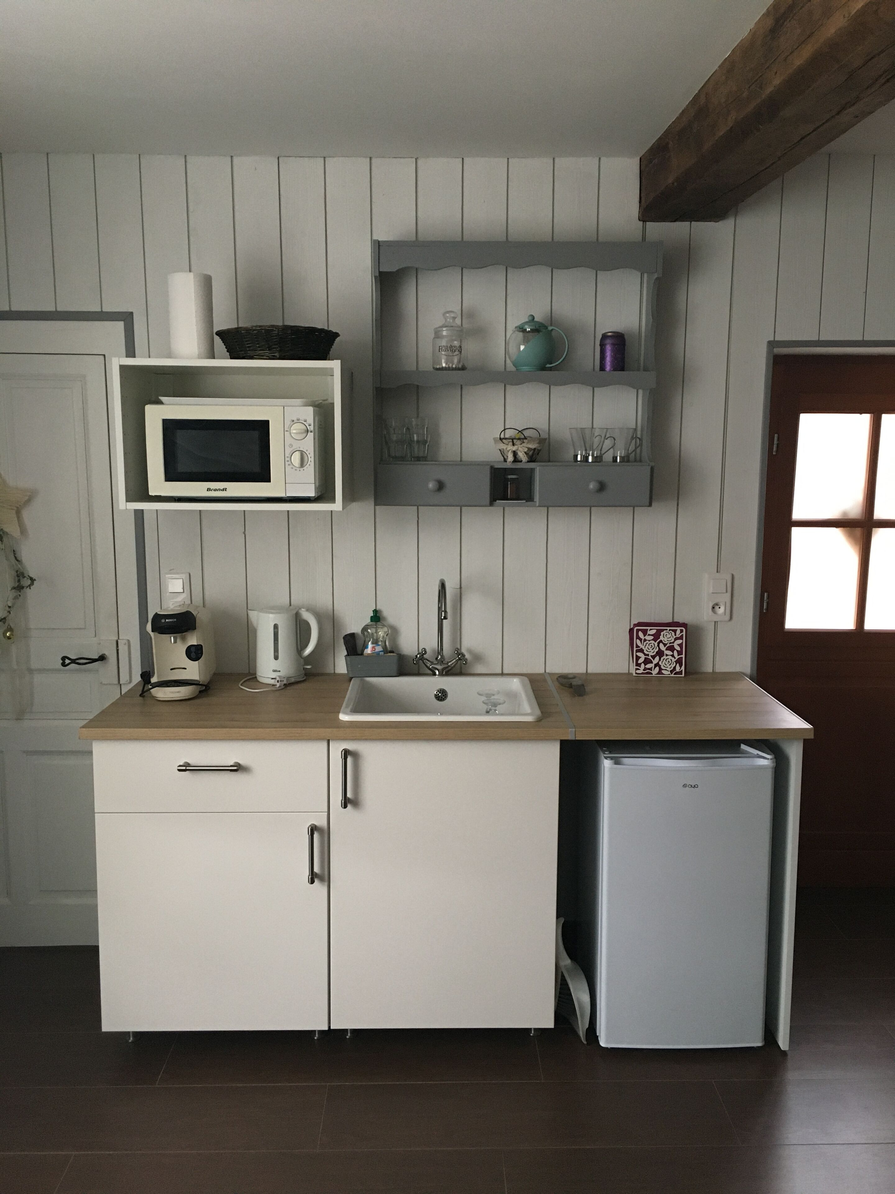 A compact kitchen with a microwave, coffee maker, sink, and a small refrigerator.