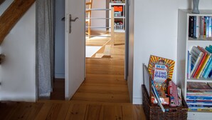 A wooden floor, a white door, a bookshelf, and a wicker basket with books.