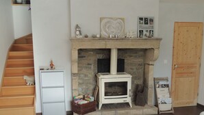 A cozy living room with a stone fireplace, a white sofa, a wooden staircase, and a door.