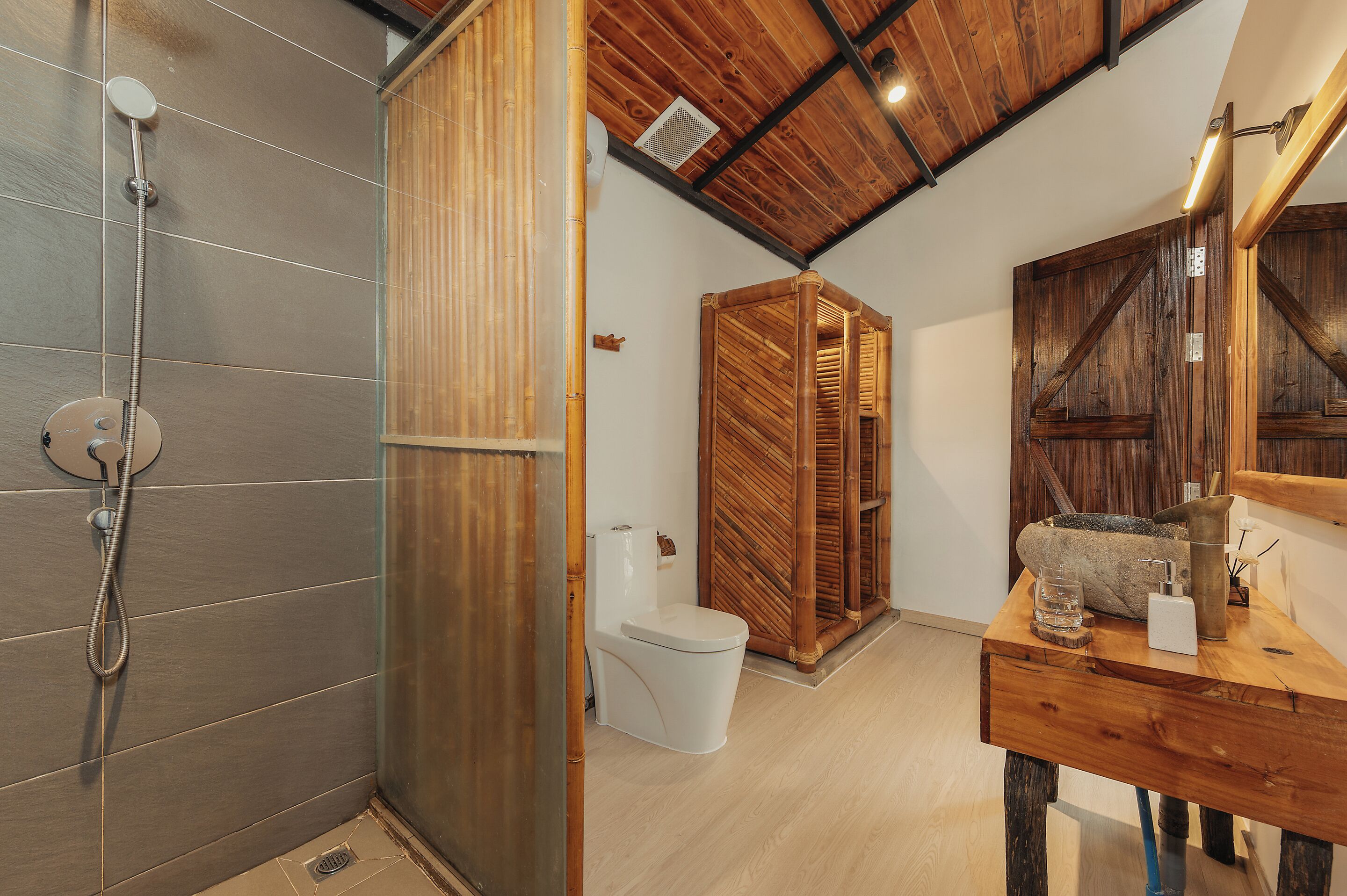 A bathroom with a shower, toilet, and wooden vanity.