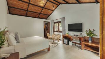 Un dormitorio con cama, escritorio, silla, televisor y planta.