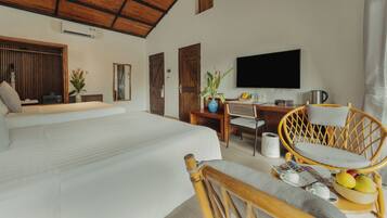 Amplia habitación con una cama grande, techo de madera, televisor, mesa de comedor con sillas y una pequeña cocina.