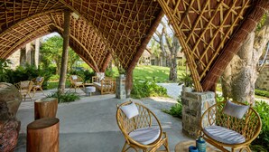 A covered outdoor seating area with wicker furniture and a stone pathway. - M Village Phu Quoc (Phu Quoc)