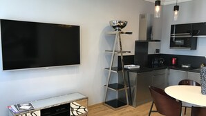 A modern kitchen with a flat-screen TV, stainless steel appliances, and a dining area with a round table and chairs. - CANNES APPART. LUXURY 50 m2 HYPER CENTER (Cannes)