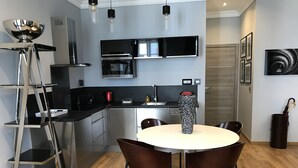 A modern kitchen with a dining area, featuring a round table, chairs, a coffee machine, and a microwave. - CANNES APPART. LUXURY 50 m2 HYPER CENTER (Cannes)