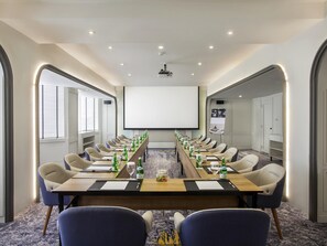A conference room with a long table, chairs, a projector screen, and a large screen. - Mercure Jakarta Batavia (Jakarta)