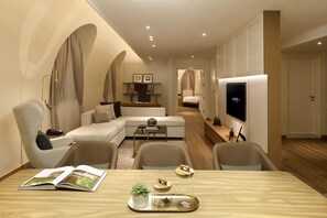 Una sala de estar moderna con un sofá, sillas, una mesa de centro, un televisor y una estantería.
