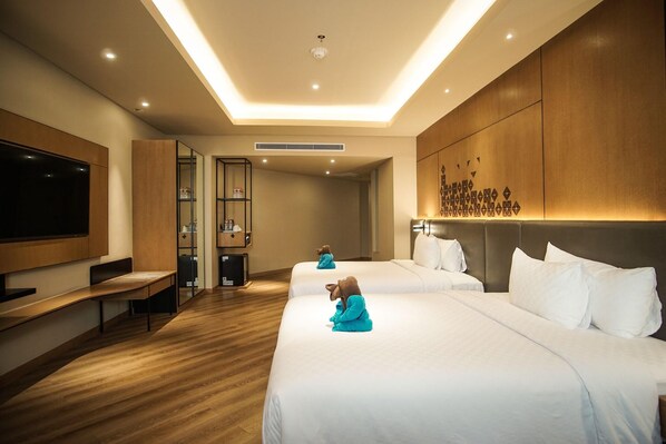 A hotel room with two beds, a TV, a bench, and a minibar. - Mercure Jakarta Batavia (Jakarta)