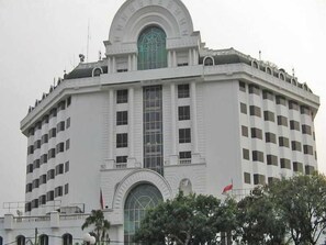 Un edificio grande y blanco de varios pisos con una entrada arqueada destacada y una cúpula en la parte superior.