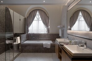Un baño moderno con bañera, dos lavamanos, un espejo grande y una cabina de ducha de cristal.