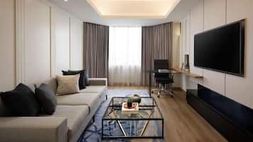 A modern living room with a sofa, coffee table, TV, and a large window with curtains.