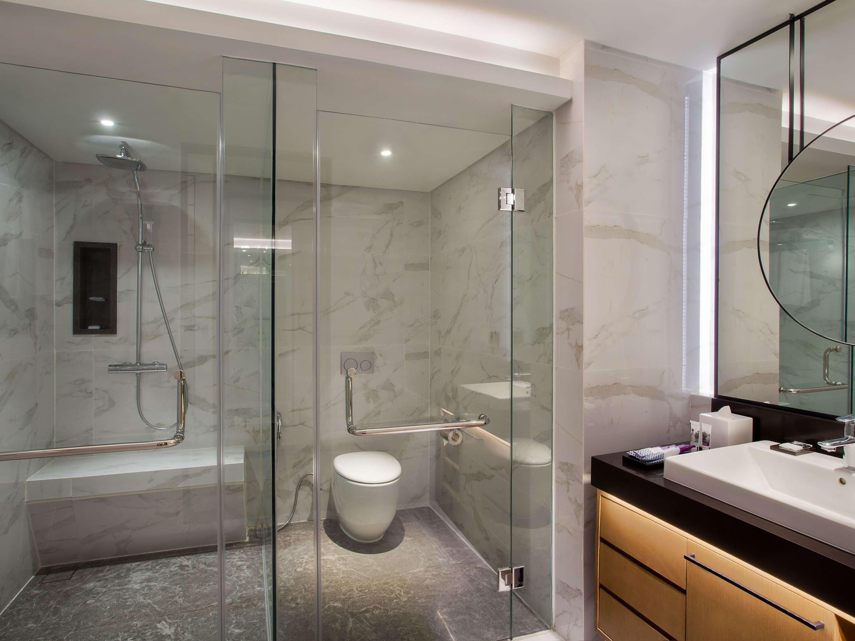 A modern bathroom with a glass-enclosed shower, a toilet, and a vanity with a sink.