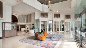 A spacious lobby with a high ceiling, a central seating area with a rug, and a glass partition on one side. - Mercure Jakarta Batavia (Jakarta)
