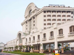Un hotel grande y blanco con una entrada imponente, varios balcones y un amplio ventanal de arco.