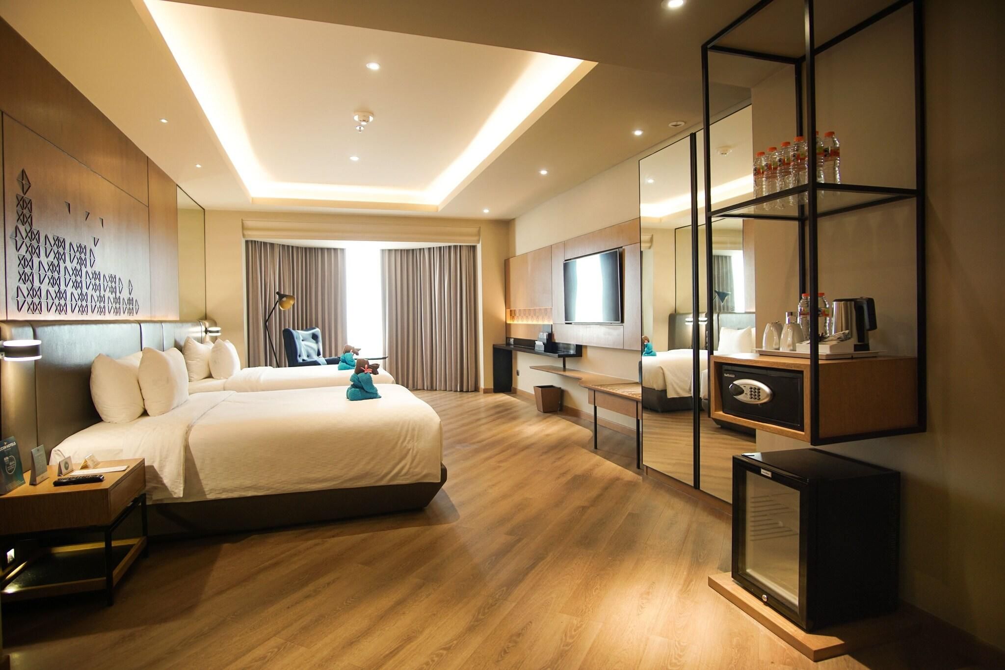 A hotel room with a large bed, a TV, a minibar, and a desk.
