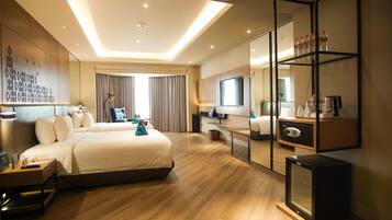 A hotel room with a large bed, a TV, a minibar, and a desk.