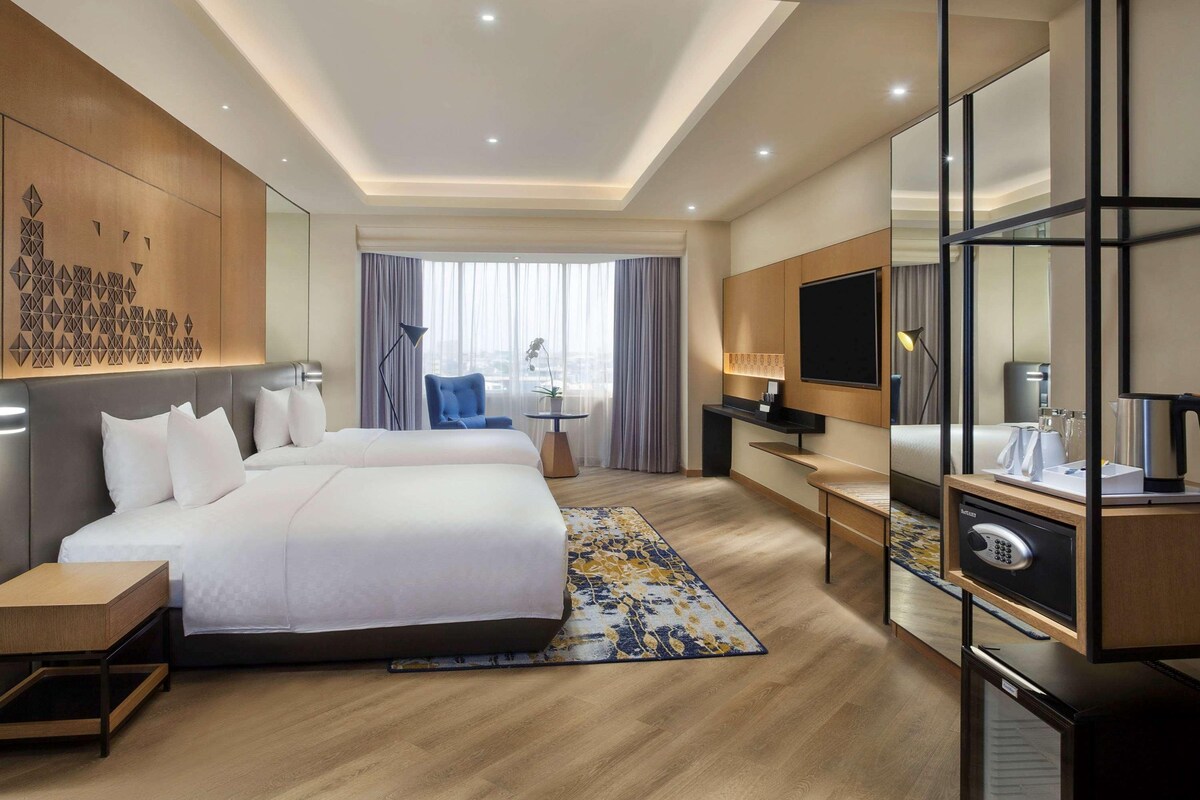 Una habitación de hotel moderna con una cama grande, un escritorio, un televisor y un minibar.