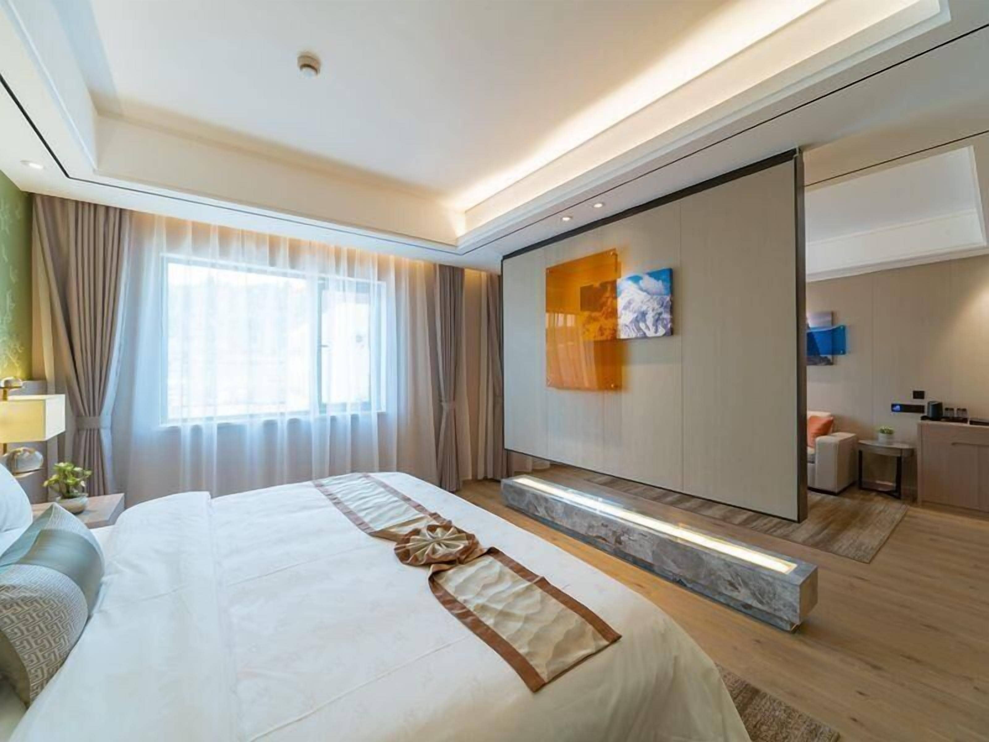 Una habitación de hotel moderna con una cama grande, un vestidor, un baño y vistas a la ciudad.