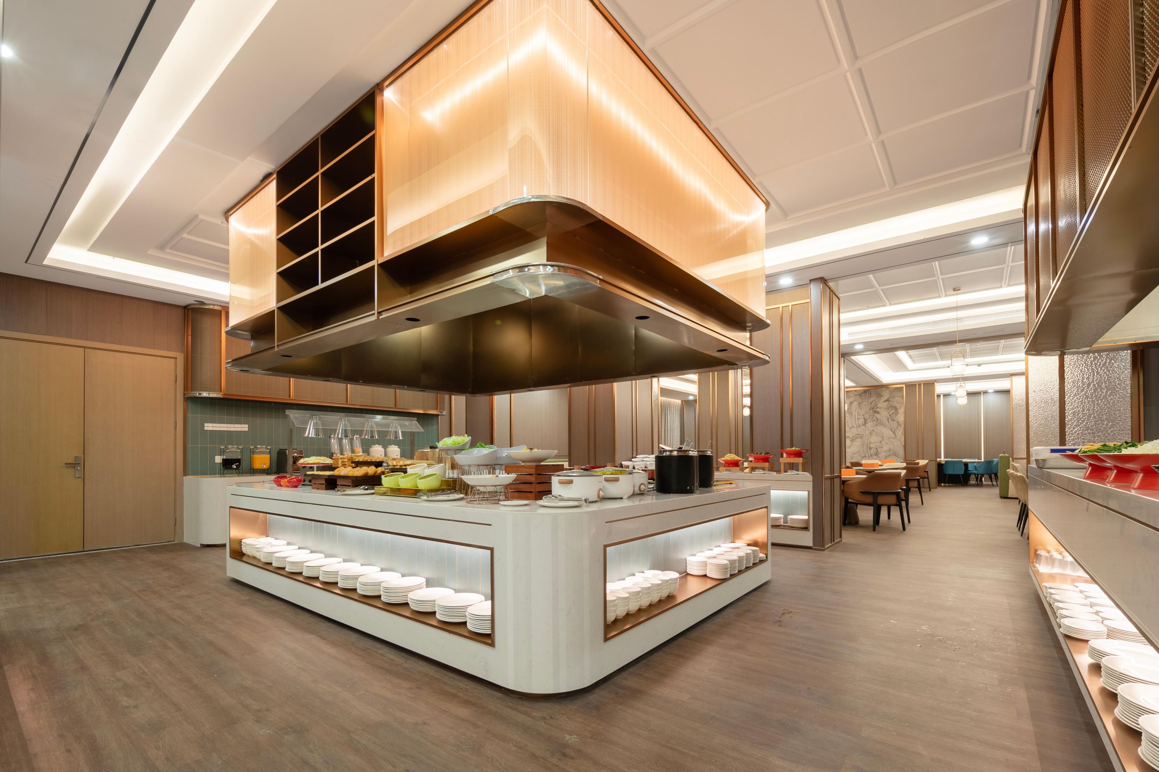 Una cocina moderna con una isla central, electrodomésticos integrados y un comedor con mesas y sillas.
