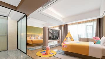 Una habitación de hotel con cama, televisión, ventana con cortinas y vistas al exterior.