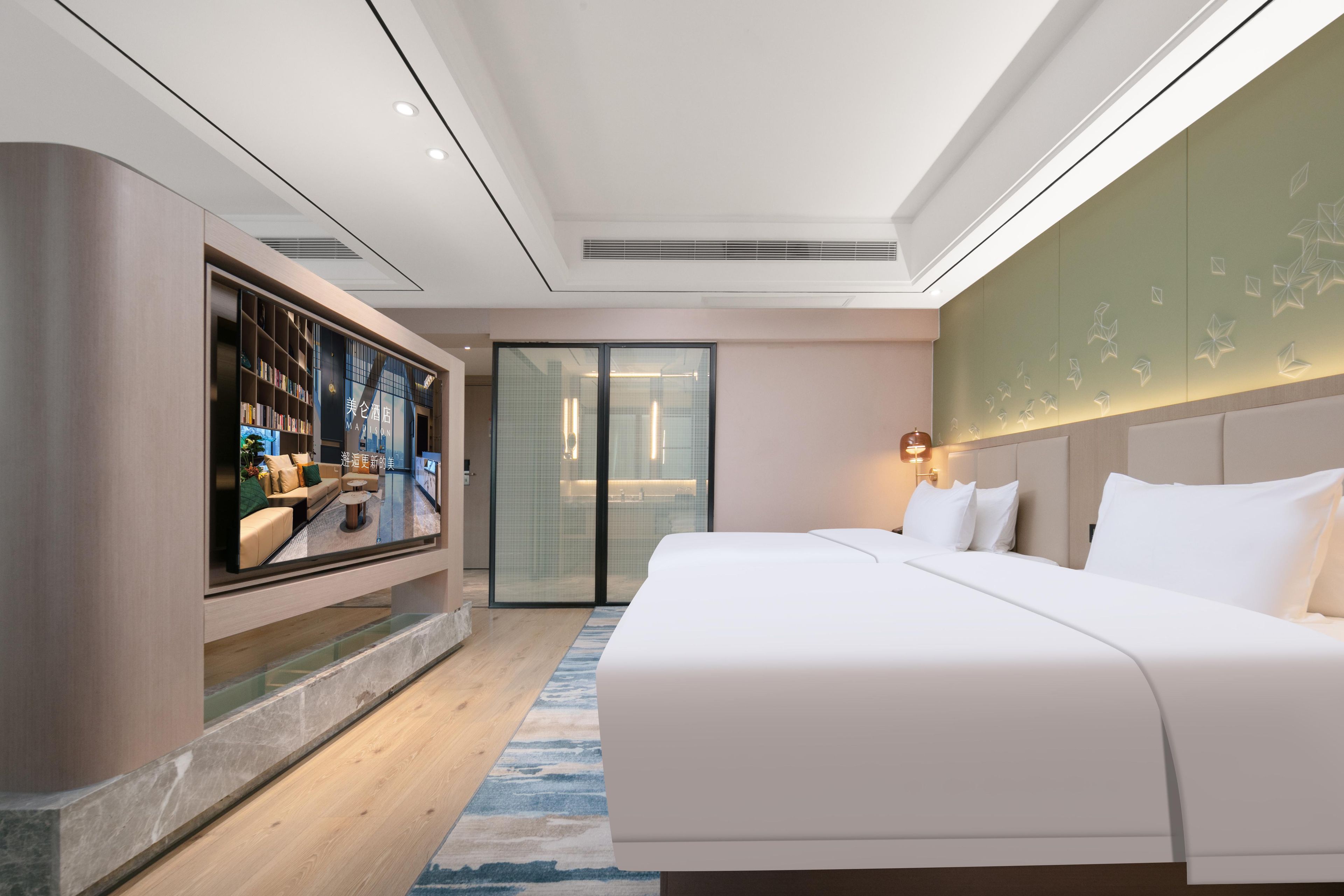 A modern hotel room with a large bed, a television, and a minibar.