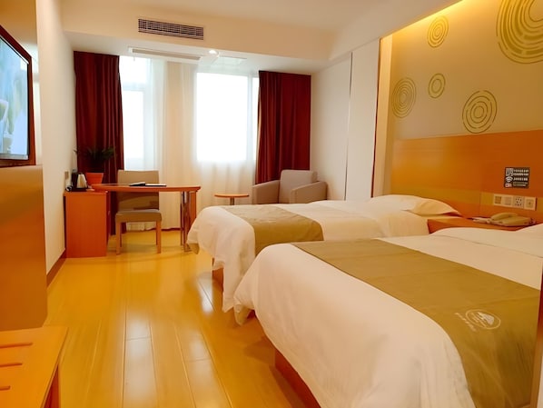 Habitación de hotel con dos camas, un escritorio, una silla, un televisor y una planta en maceta.