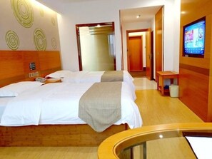 A hotel room with a large bed, a TV, and a wooden floor.