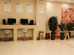 A reception area with a counter, two bar stools, a potted plant, and a wall-mounted sign. - Greentree Inn Fuyang Technician College (Fuyang)