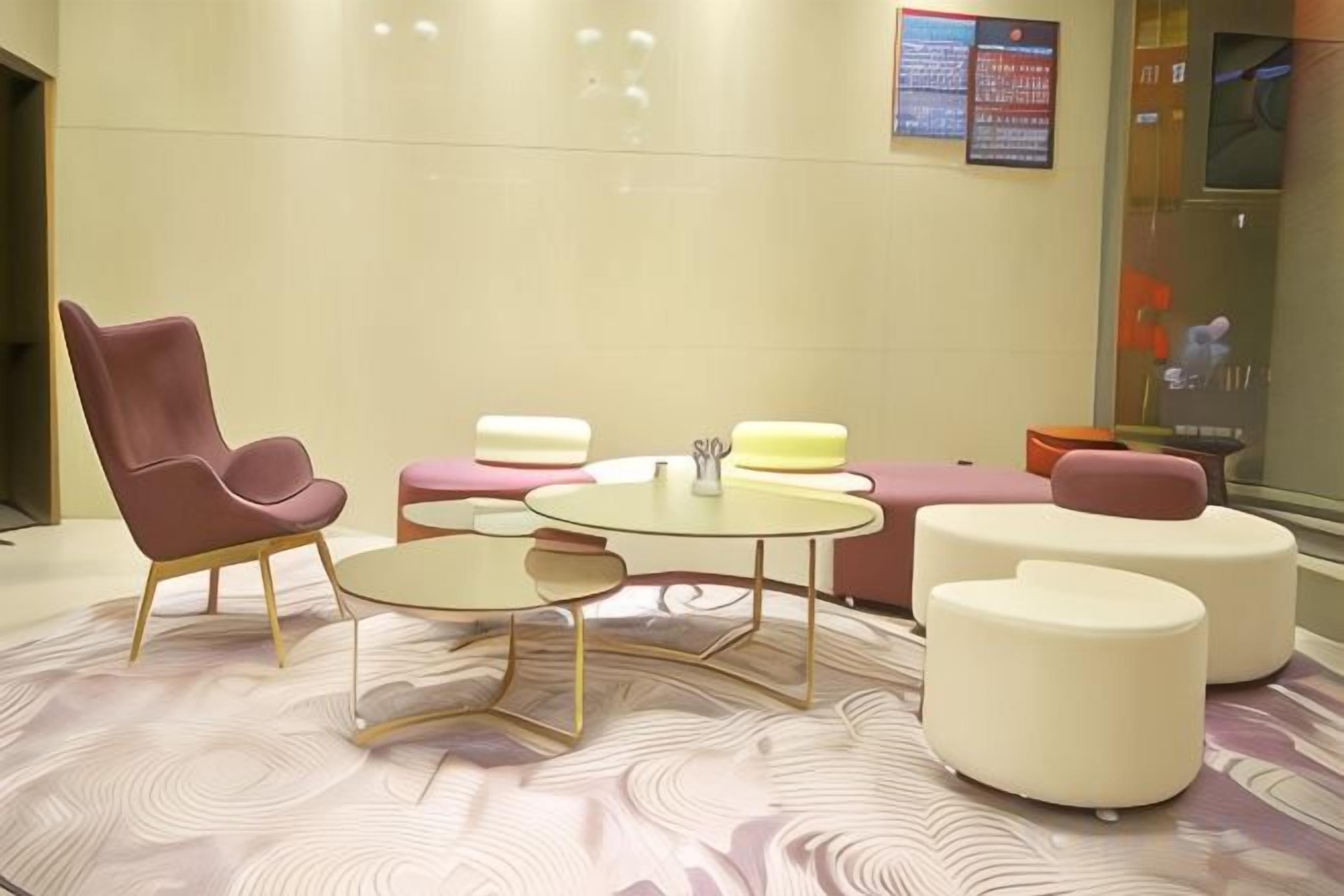 A modern lounge area with a plush chair, round tables, and a sofa.