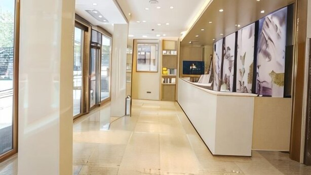 A hotel reception area with a modern design, a reception desk, and framed artwork on the walls. - Lavande Hotel (Guilin Longsheng) (Longsheng)