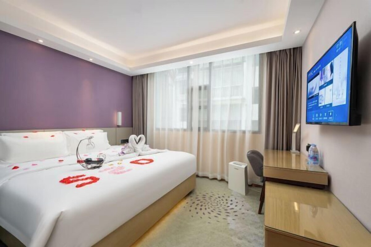 Ein Hotelzimmer mit Bett, Schreibtisch, Fernseher und einem Fenster mit Vorhängen.