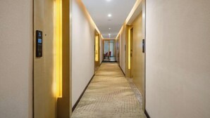 A hotel hallway with carpeted floors, doors on both sides, and a light source at the end. - Lavande Hotel (Guilin Longsheng) (Longsheng)
