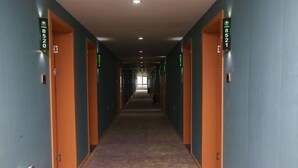Pasillo de hotel con puertas numeradas 8520 y 8521, pisos alfombrados y señalización de salida de emergencia.