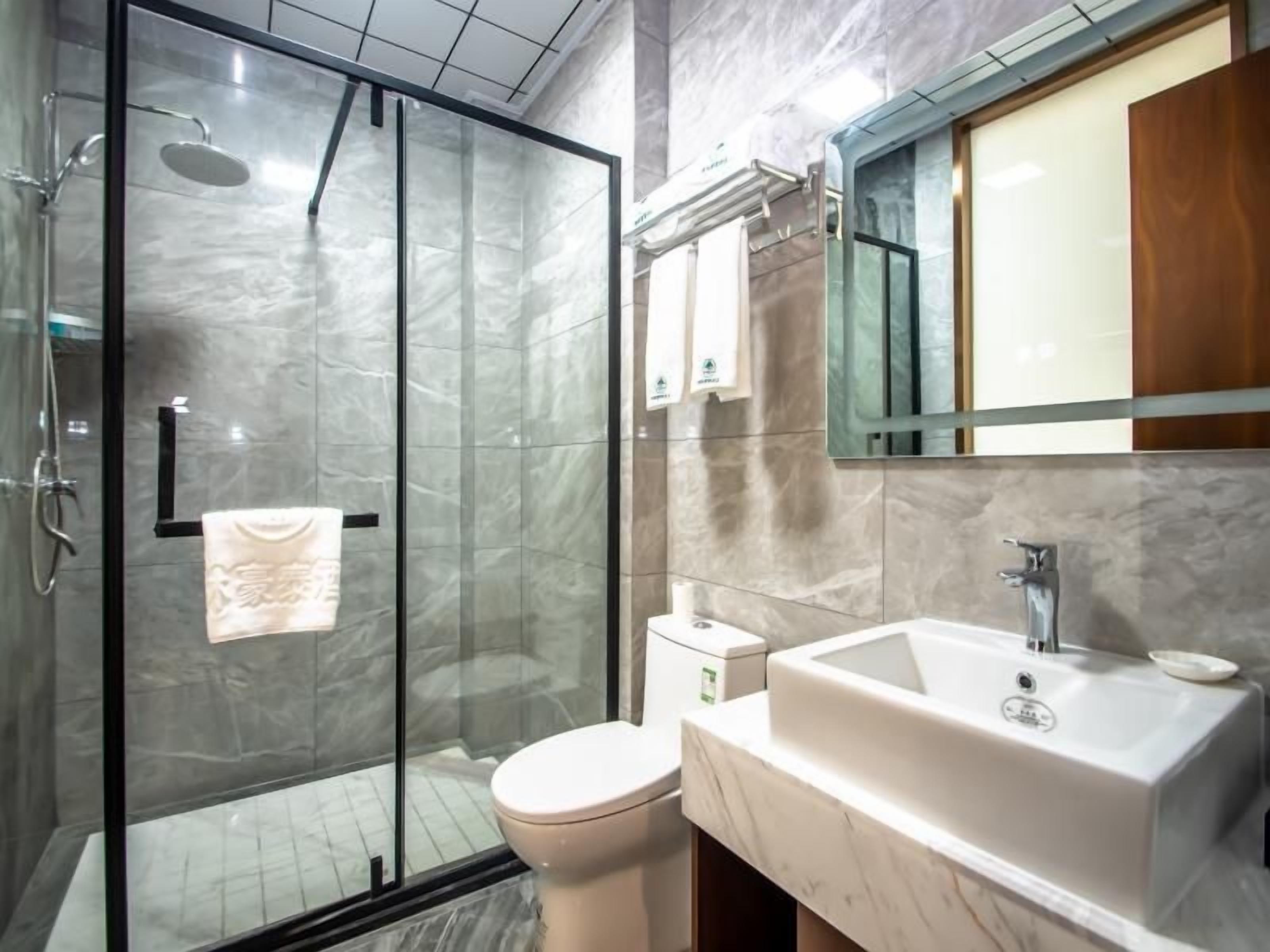 A modern bathroom with a glass-enclosed shower, a white sink, and a toilet.