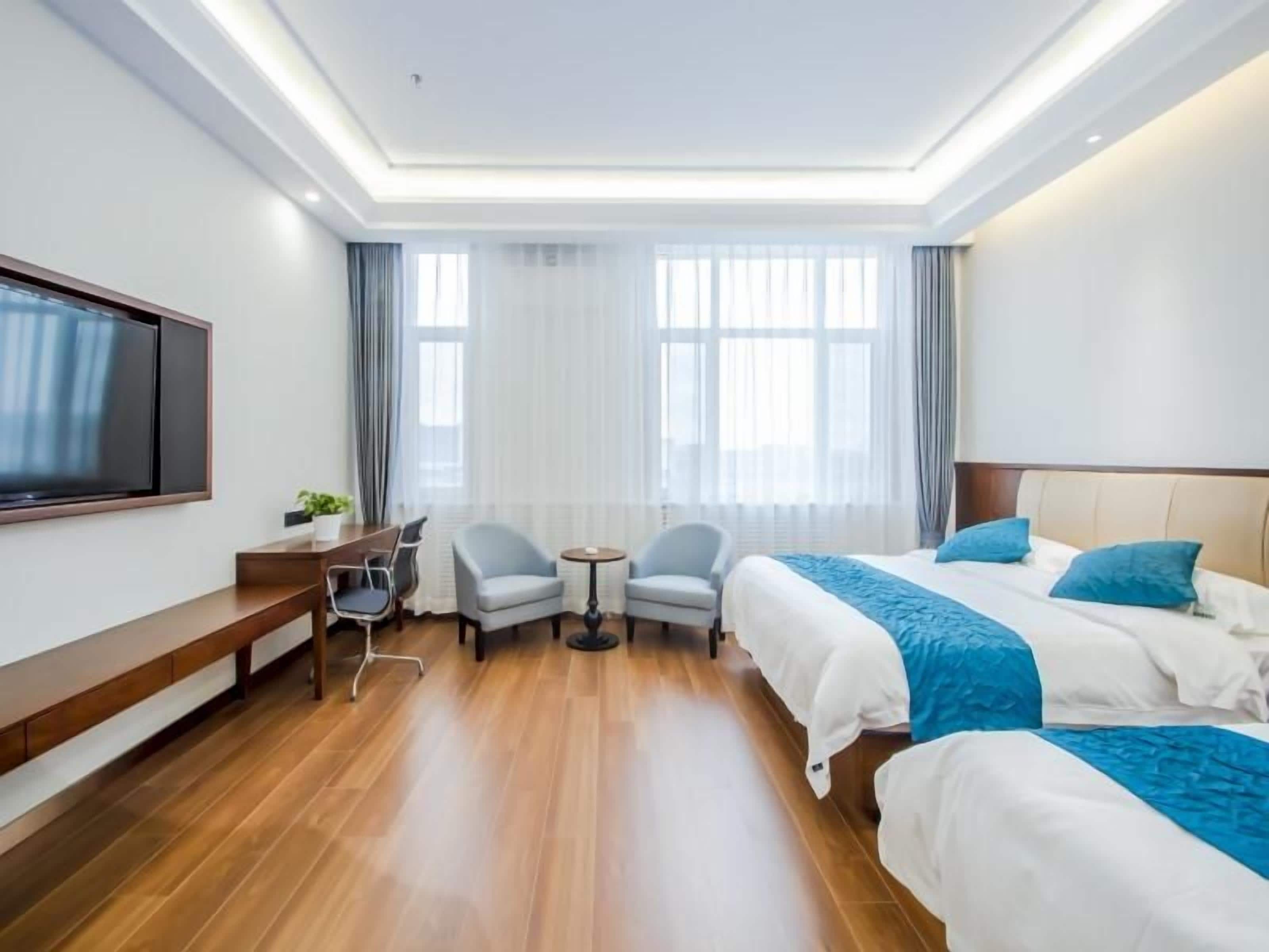 A hotel room with a bed, a desk, a chair, and a television.
