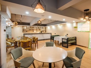 Un comedor moderno con una mesa redonda y sillas, una cocina al fondo e iluminación colgante.