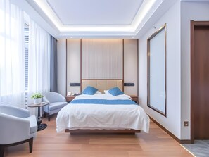 A modern hotel room with a large bed, a bedside table, a chair, and a large window with curtains. - Greentree Inn Yinchuan International Trade Market (Yinchuan)