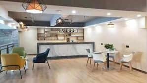 Un área de comedor moderna con encimera de mármol, sillas de madera e iluminación colgante.