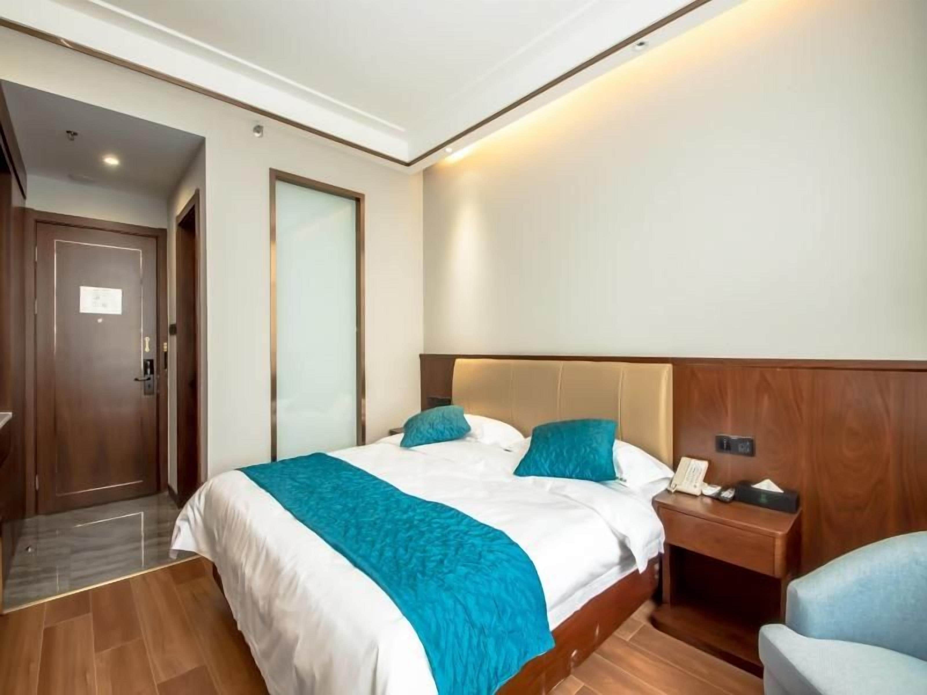 Una habitació d'hotel amb un llit, una taula de nit amb un telèfon, una cadira i una porta.